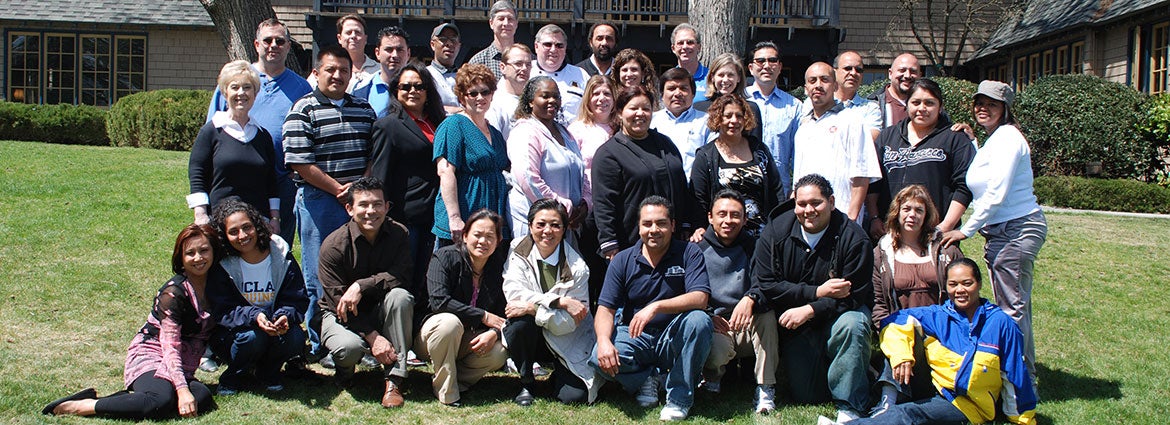 Group of mentor program members posing in front of the lodge smiling for a group photo.