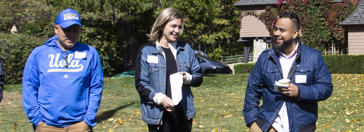 Three members of the program chatting on the lawn while walking.